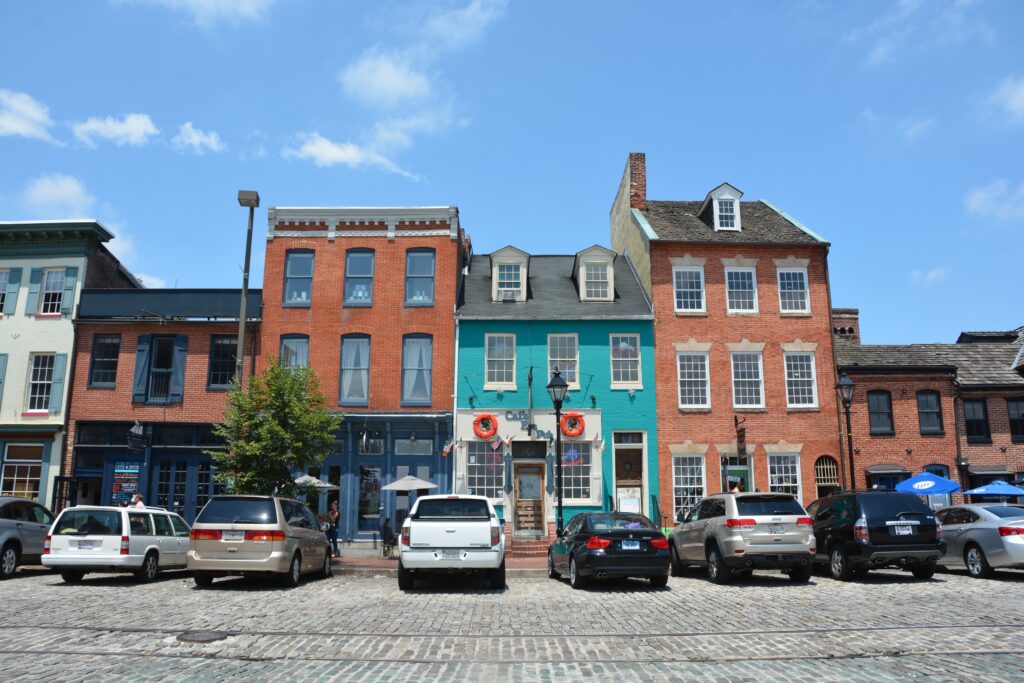 Színes homlokzatú sorházak Baltimore történelmi városrészében, téglafalakkal és díszített ablakokkal Maryland államban